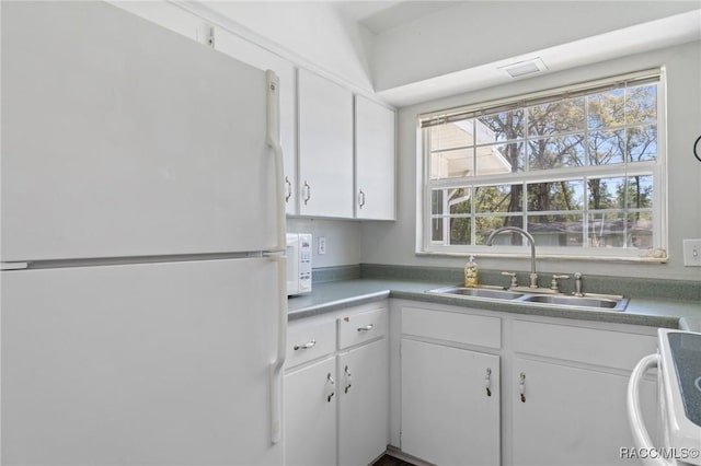 kitchen with white appliances, white cabinetry, and a sink