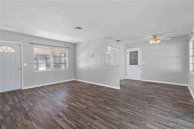 unfurnished living room with a ceiling fan, dark wood finished floors, visible vents, and baseboards