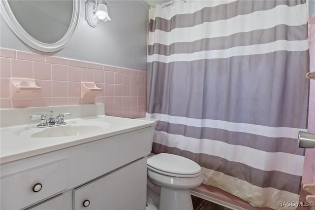 full bath featuring a shower with shower curtain, tile walls, toilet, and vanity