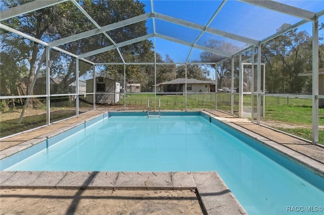 pool featuring a lanai, an outdoor structure, a lawn, and a shed