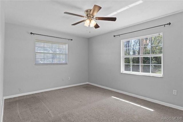 carpeted empty room featuring baseboards and a ceiling fan