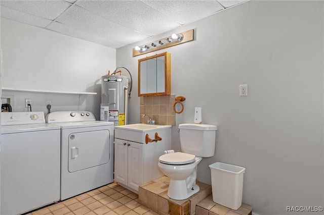 clothes washing area with laundry area, water heater, separate washer and dryer, and a sink