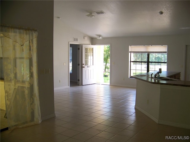 spare room with a textured ceiling, lofted ceiling, sink, and light tile patterned floors