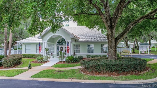 ranch-style home with stucco siding, a tile roof, and fence