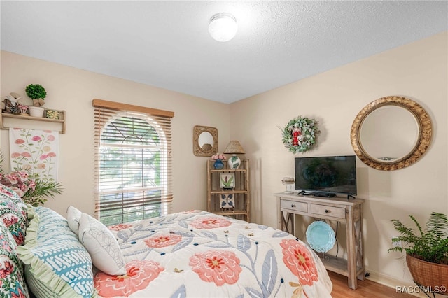 bedroom with light wood-style flooring, a textured ceiling, and baseboards