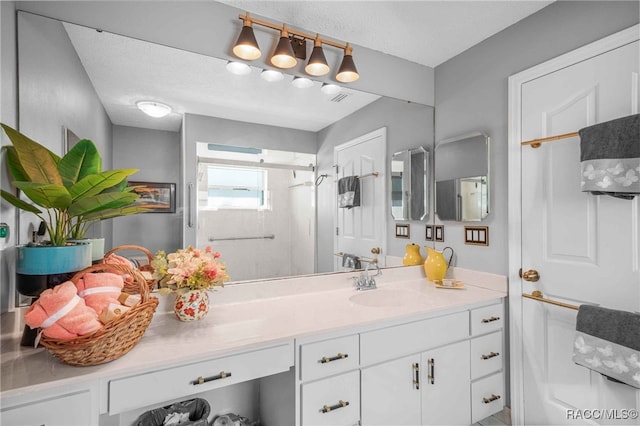 full bath featuring visible vents, a textured ceiling, a stall shower, and vanity