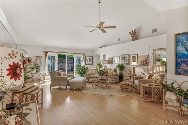 living area featuring wood finished floors, visible vents, high vaulted ceiling, ceiling fan, and a textured ceiling