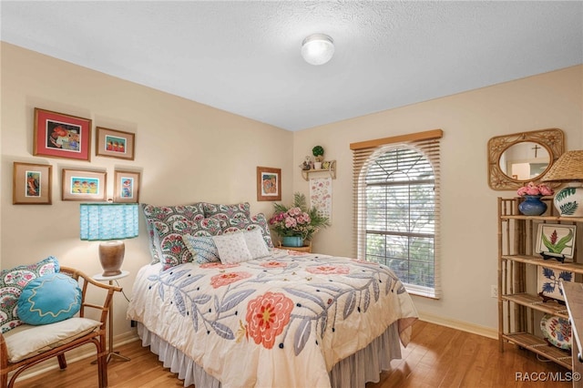 bedroom with wood finished floors, baseboards, and a textured ceiling