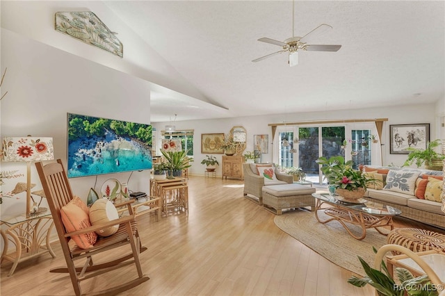 living room featuring lofted ceiling, a textured ceiling, light wood-type flooring, and a ceiling fan