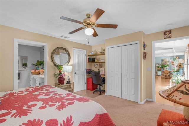 bedroom with visible vents, ceiling fan, multiple closets, a textured ceiling, and light carpet