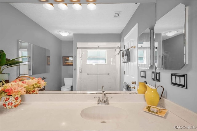 bathroom with vanity, visible vents, a shower stall, a textured ceiling, and toilet