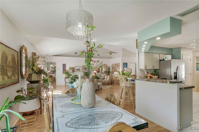 dining room with visible vents, light wood-style flooring, ceiling fan with notable chandelier, recessed lighting, and vaulted ceiling