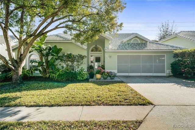 ranch-style house featuring a front yard, an attached garage, stucco siding, concrete driveway, and a tiled roof