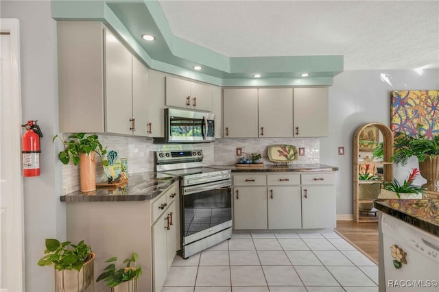 kitchen featuring tasteful backsplash, a textured ceiling, stainless steel appliances, and dark countertops