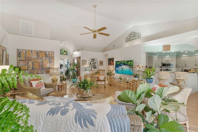 living room with light wood finished floors, visible vents, high vaulted ceiling, and a ceiling fan