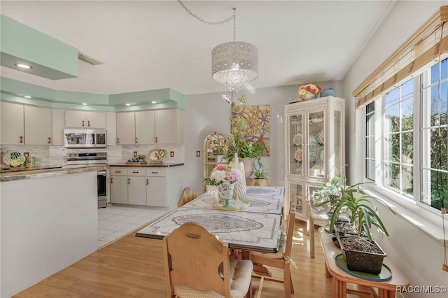 dining space with light wood-style flooring, recessed lighting, visible vents, and a chandelier