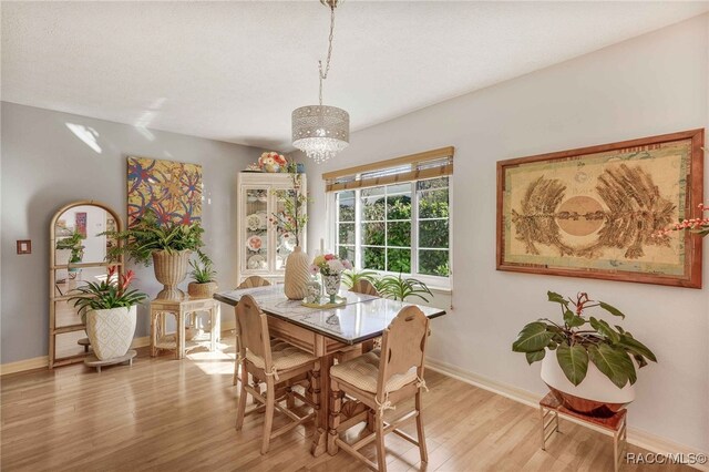 dining space featuring light wood-type flooring, baseboards, and a textured ceiling