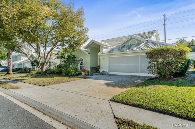 single story home with stucco siding, concrete driveway, a front yard, a garage, and a tiled roof