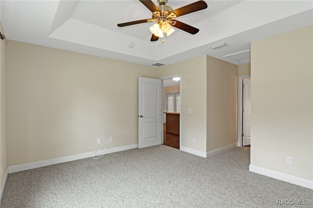 unfurnished room with a raised ceiling, ceiling fan, and carpet floors