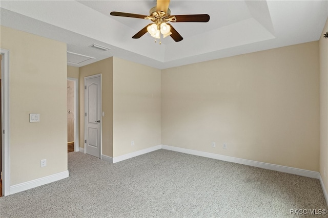 empty room with ceiling fan, a raised ceiling, and carpet floors