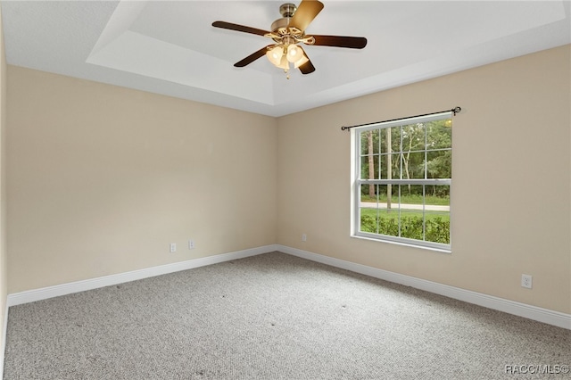 carpeted empty room with a tray ceiling and ceiling fan