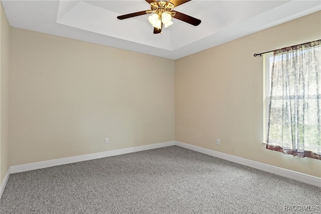 carpeted spare room with a tray ceiling and ceiling fan