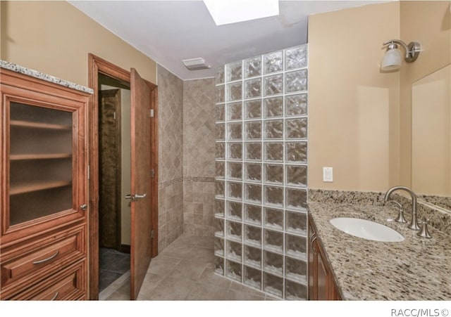 bathroom with a tile shower, tile patterned flooring, and vanity