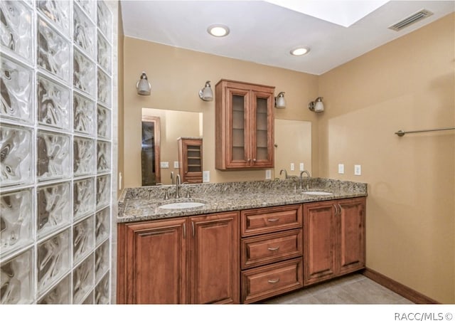 bathroom featuring tile patterned flooring, vanity, and a skylight