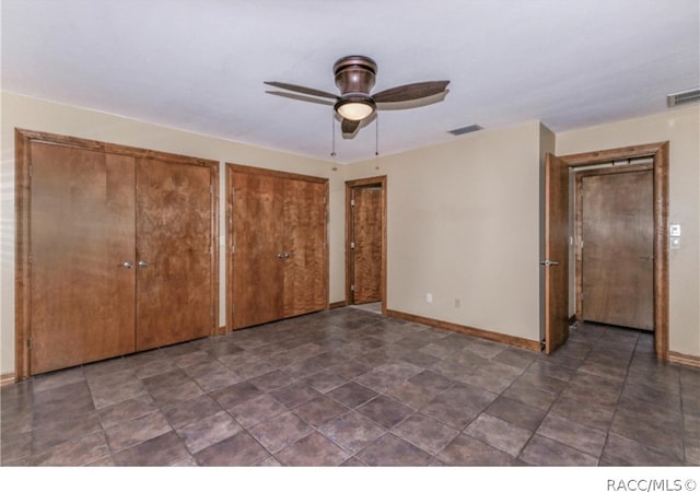 unfurnished bedroom with ceiling fan and multiple closets