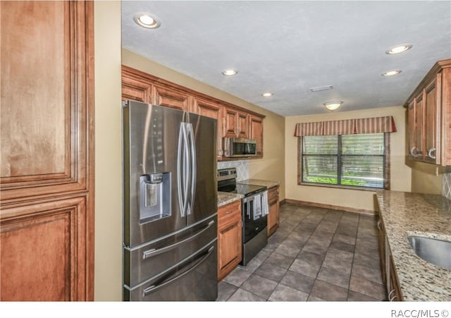 kitchen with light stone countertops and appliances with stainless steel finishes