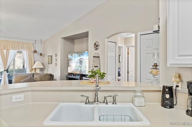 kitchen with white cabinets, sink, and vaulted ceiling