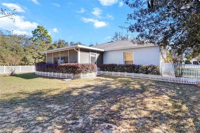 rear view of house featuring a sunroom and a lawn