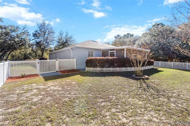 view of side of home featuring a yard, a fenced backyard, and stucco siding