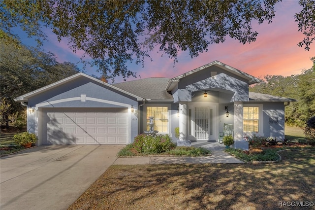 single story home featuring concrete driveway, an attached garage, and stucco siding