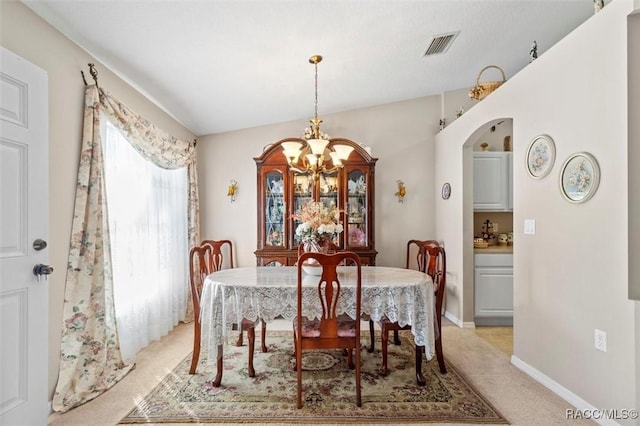 carpeted dining area featuring an inviting chandelier and vaulted ceiling