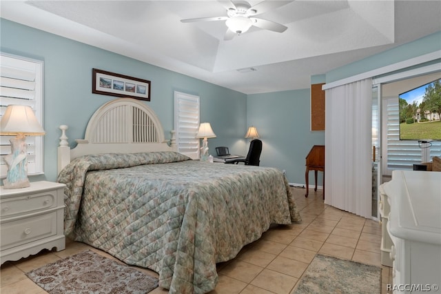 bedroom with ceiling fan, light tile patterned floors, and a tray ceiling