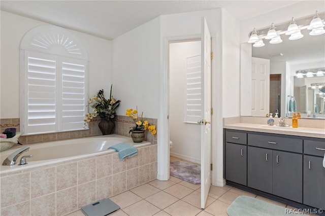 bathroom featuring tiled tub, tile patterned flooring, vanity, and toilet