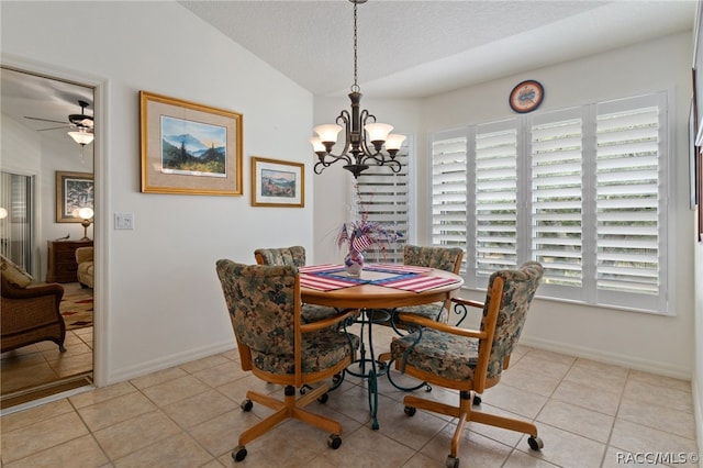 dining space with a textured ceiling, ceiling fan with notable chandelier, light tile patterned floors, and vaulted ceiling