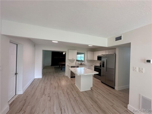 10765 W Spring Cir, Crystal River, FL 34428 - kitchen with appliances with stainless steel finishes, a sink, light wood finished floors, white cabinets, and baseboards