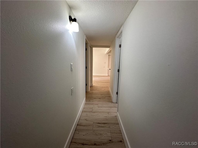 10765 W Spring Cir, Crystal River, FL 34428 - hall featuring light wood finished floors, baseboards, and a textured ceiling