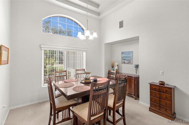 9989 N Langdon Rd, Citrus Springs, FL 34434 - dining room featuring light colored carpet, a chandelier, and a towering ceiling