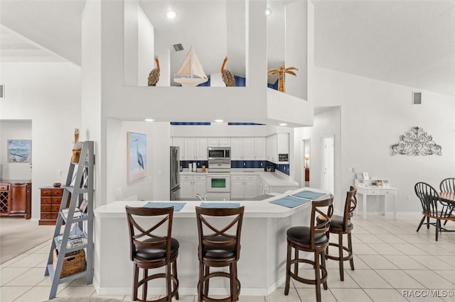 9989 N Langdon Rd, Citrus Springs, FL 34434 - kitchen with stainless steel appliances, high vaulted ceiling, a kitchen breakfast bar, light countertops, and light tile patterned flooring