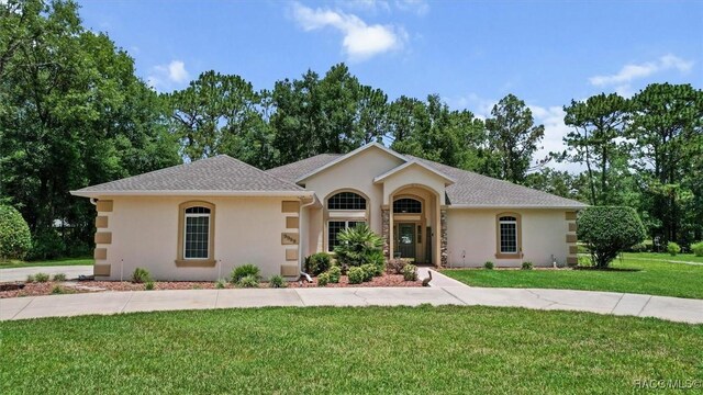 9989 N Langdon Rd, Citrus Springs, FL 34434 - single story home featuring stucco siding, a front lawn, and view of wooded area