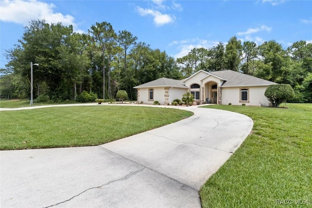 9989 N Langdon Rd, Citrus Springs, FL 34434 - single story home featuring a front lawn, stucco siding, curved driveway, and view of wooded area