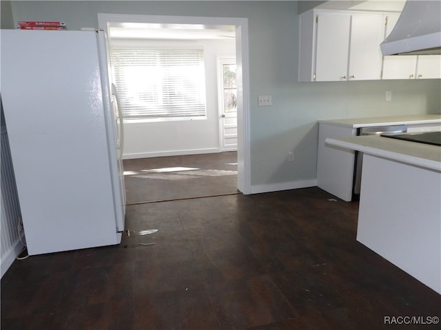 kitchen with wall chimney exhaust hood, white cabinets, white fridge, and dark wood-type flooring