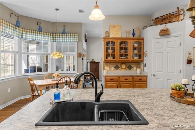 kitchen with decorative light fixtures, light countertops, visible vents, a sink, and wood finished floors