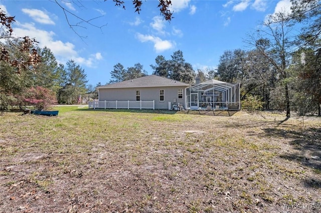 back of house with a yard, a lanai, and stucco siding