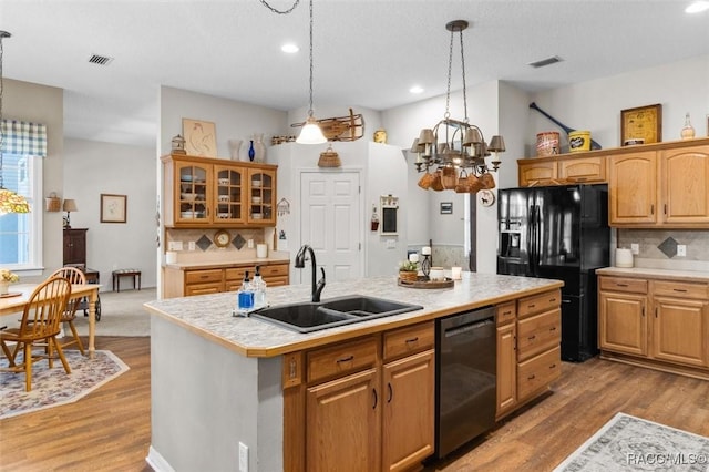 kitchen featuring a sink, visible vents, light countertops, black appliances, and tasteful backsplash