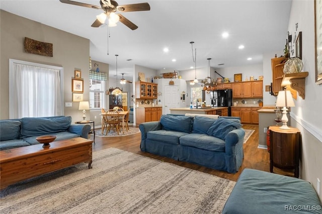 living room with recessed lighting, light wood finished floors, and ceiling fan with notable chandelier