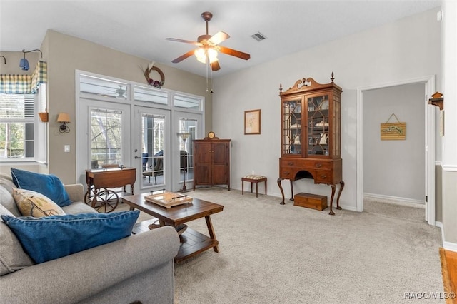 living area featuring light carpet, visible vents, baseboards, ceiling fan, and french doors